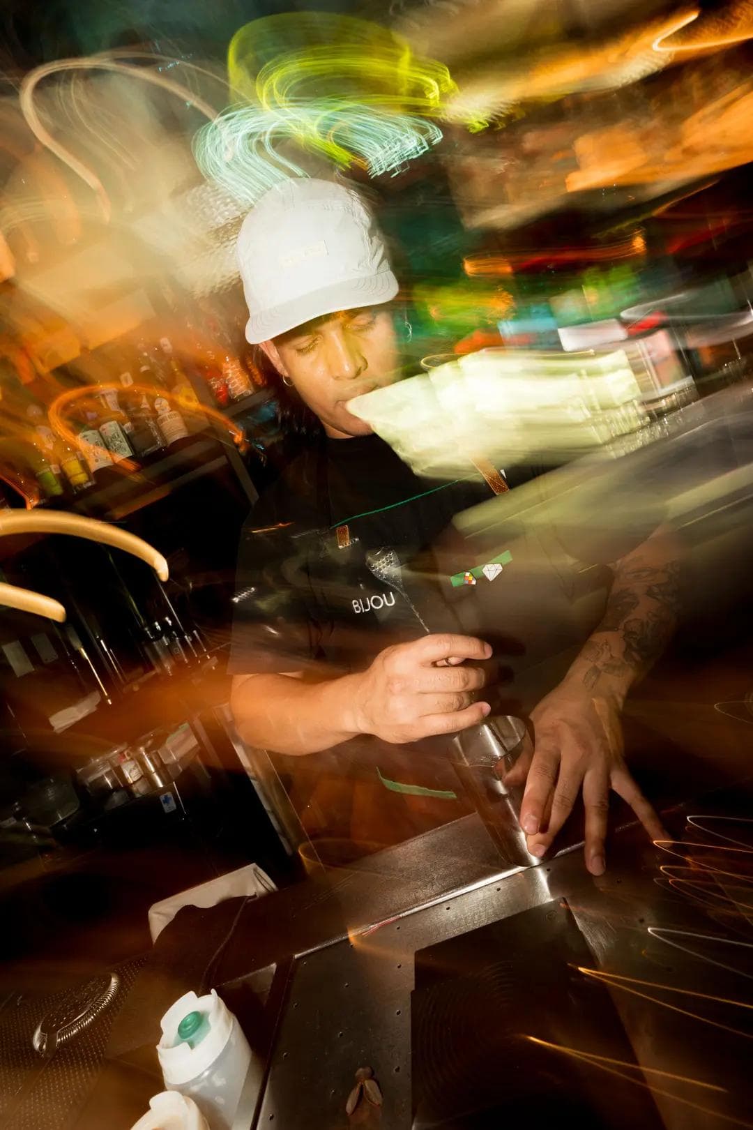 Dynamic shot of a bartender crafting a cocktail at Bijou, surrounded by vibrant light trails that capture the energetic and modern vibe of the bar.